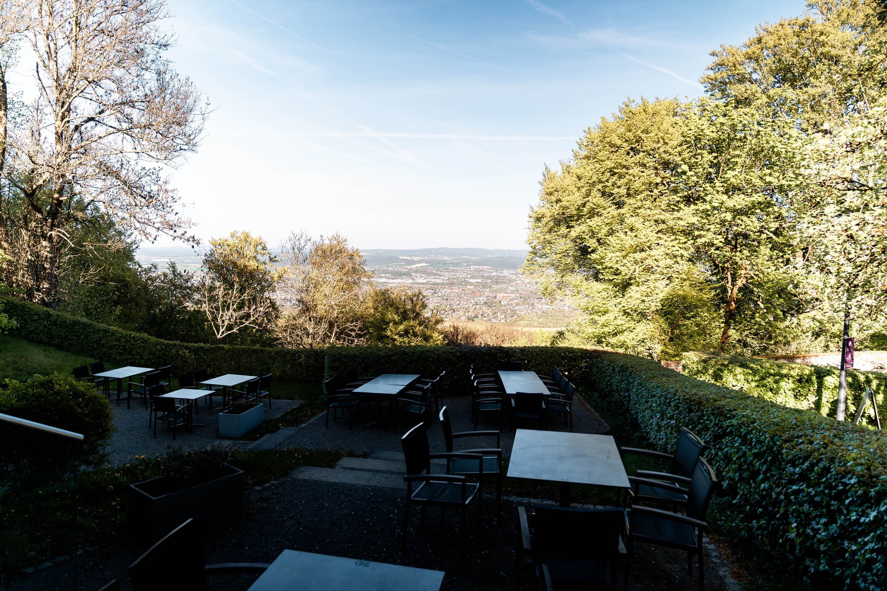 Außenterrasse mit Bistrostühlen und festlich gedeckten Tischen zur goldenen Stunde.